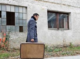 Side view of man with suitcase walking outdoors. photo