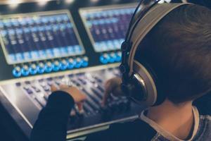 niño pequeño con auriculares editando música en estudio de grabación. foto