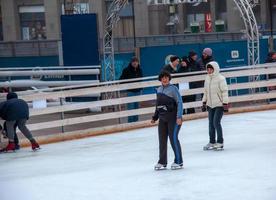 People have fun skating on a public ice rink built by the municipality on the streets of the city during Christmas photo