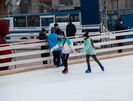 People have fun skating on a public ice rink built by the municipality on the streets of the city during Christmas photo