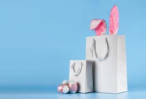 Banner on a blue background. The concept of online shopping for Easter, purchases and sale for the holiday. Gift bag with bunny ears and Easter eggs photo