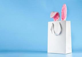 Wide banner on a blue background. The concept of online shopping for Easter, purchases and sale for the holiday. Gift bag with bunny ears photo