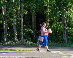 06.08.2021 Kazan, Russia A woman with food is walking along the bike path. People in the park photo