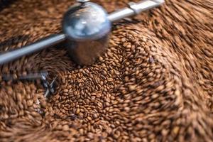 Best coffee background. Freshly roasted coffee beans in motion. Artistic hot beverage closeup concept. Coffee roaster cylinder roasting and mixing coffee beans photo