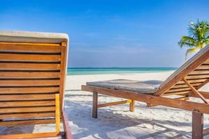 hermosa playa. un par de sillas en la playa de arena cerca del mar, paisaje insular borroso costa exótica. vacaciones de verano y concepto de vacaciones de ensueño para el turismo. inspirador hotel tropical resort. foto