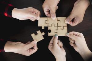 Hands of diverse people assembling jigsaw puzzle, team put pieces together searching for right match, help support in teamwork to find common solution concept, top close up view photo