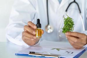 Doctor holding a bottle of hemp oil, Medical marijuana products including cannabis leaf, cbd and hash oil, alternative remedy or medication,medicine concept. photo