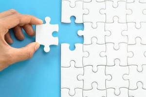 White jigsaw in the hands, The correct solution. Teamwork, Solving and completing the task. Last piece of jigsaw puzzle. Assembling  jigsaw puzzle pieces. photo