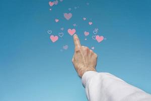 hand up in the sky touching a heart shape, love emotions in valentine's day photo