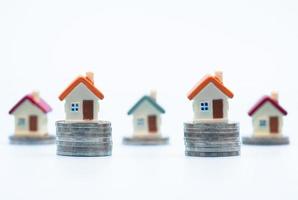 Mini house on stack of coins  on white background., Concept of Investment property, Investment risk and uncertainty in the real estate housing market. photo