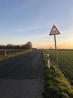 calle en el campo con un cartel que advierte a los conductores que los ciclistas pueden cruzarla foto