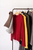 Row of different colorful Knitted sweaters hang on hangers, white background photo