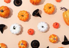 pattern of colorful artificial pumpkins and halloween hats on orange background photo