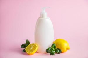 Organic cosmetics with lemon oil. Bottle of moisturizer with citrus on a pink background. photo