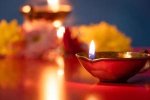 Happy Diwali. Burning diya oil lamps and flowers on blue background. Traditional Indian festival of light. photo