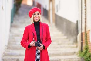 Cheerful female traveler with camera smiling on narrow street during vacation photo