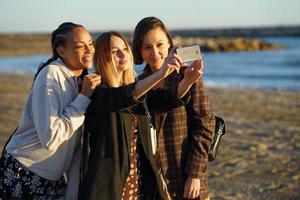 Content diverse women taking selfie on coast photo