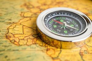 Bangkok, Thailand - January 20, 2022 Compass for navigation on vintage old antique world map background to travel, geography, tourism and exploration concept. photo