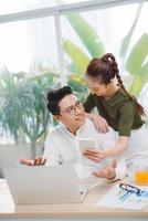 Young man and woman working on laptop and using mobile phone relax in business office photo