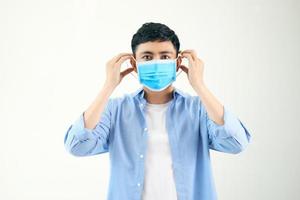 COVID-19 Coronavirus portrait handsome young asian man wearing mask protection from covid 19 isolated on white background in studio. Asian man people. COVID-19 concept. photo