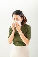 Woman with a cold blowing her runny nose with tissue photo