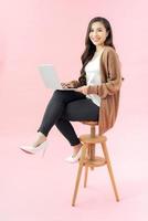 Smilling young woman using laptop pc computer isolated on the blue background photo