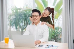 Wide shot of gorgeous lady and sir surfing in laptop while sitting at table photo