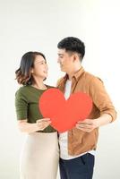 Smiling loving couple holding heart shape over white background. photo