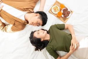 Romantic couple having breakfast lying in the bed at home photo