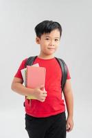un escolar con mochila sosteniendo un cuaderno aislado de fondo blanco foto