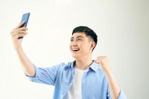 Handsome smiling man is standing, holding telephone and taking a selfie photo