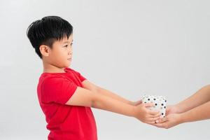 Portrait of a happy cute little kid holding gift box and looking at camera isolated over white background photo