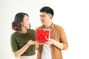 Portrait of happy couple in casual wear standing, holding box with present and looking at camera together photo