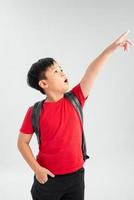 Beautiful student kid boy wearing backpack holding book over isolated white background very happy pointing with hand and finger to the side photo