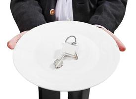 el hombre de negocios sostiene un plato blanco con nuevas llaves de puerta foto