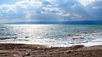 dirty beach of Dead Sea in cloudy winter day photo