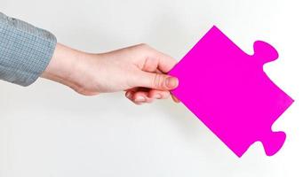 pieza de rompecabezas rosa en mano femenina foto