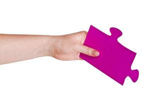 mano femenina sosteniendo una gran pieza de rompecabezas de papel rosa foto
