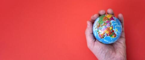 Globe in hand on red and paper background with space for text. photo