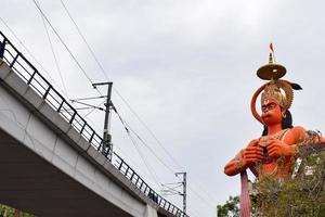 New Delhi, India - June 21, 2022 - Big statue of Lord Hanuman near the delhi metro bridge situated near Karol Bagh, Delhi, India, Lord Hanuman statue touching sky photo