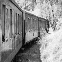 Toy Train moving on mountain slope, beautiful view, one side mountain, one side valley moving on railway to the hill, among green natural forest.Toy train from Kalka to Shimla in India-Black and White photo