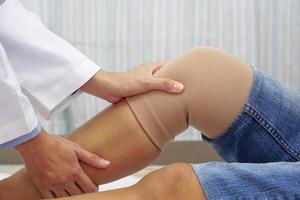 médico examinando la rodilla de un paciente con un vendaje. concepto de control de salud, atención médica y médica. foto
