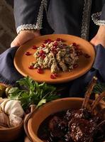 A vertical shot of a waitress presenting a kuchmachi and tomahawk steak in the background photo