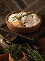 A vertical shot of a chicken covered in a creamy sauce photo