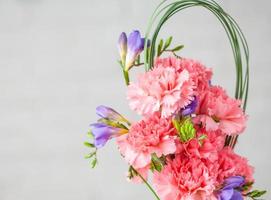 A closeup of a beautiful composition with pink spray carnations and freesia isolated on a white background photo