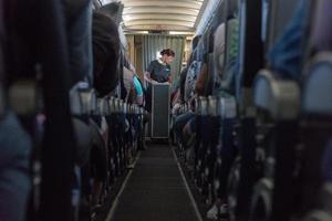 An angle shot of a stewardess passing something to passengers. photo