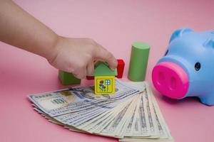 Hand of the kids take a wood block with small  house models on top of block.Concept of saving money for future , investment property and saving money to buy a house. On blur background. photo