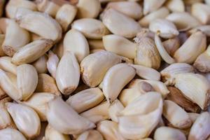 White garlic pile texture. Fresh garlic on market table closeup photo. Vitamin healthy food spice image. Spicy cooking ingredient picture. Pile of white garlic heads. photo