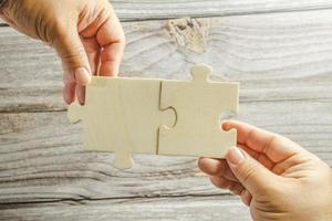 White jigsaw puzzle connecting together. Team business success partnership or teamwork concept. A group of business people assembling jigsaw puzzle. Business solutions, success and strategy concept. photo