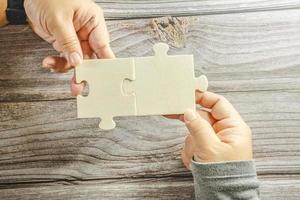 White jigsaw puzzle connecting together. Team business success partnership or teamwork concept. A group of business people assembling jigsaw puzzle. Business solutions, success and strategy concept. photo